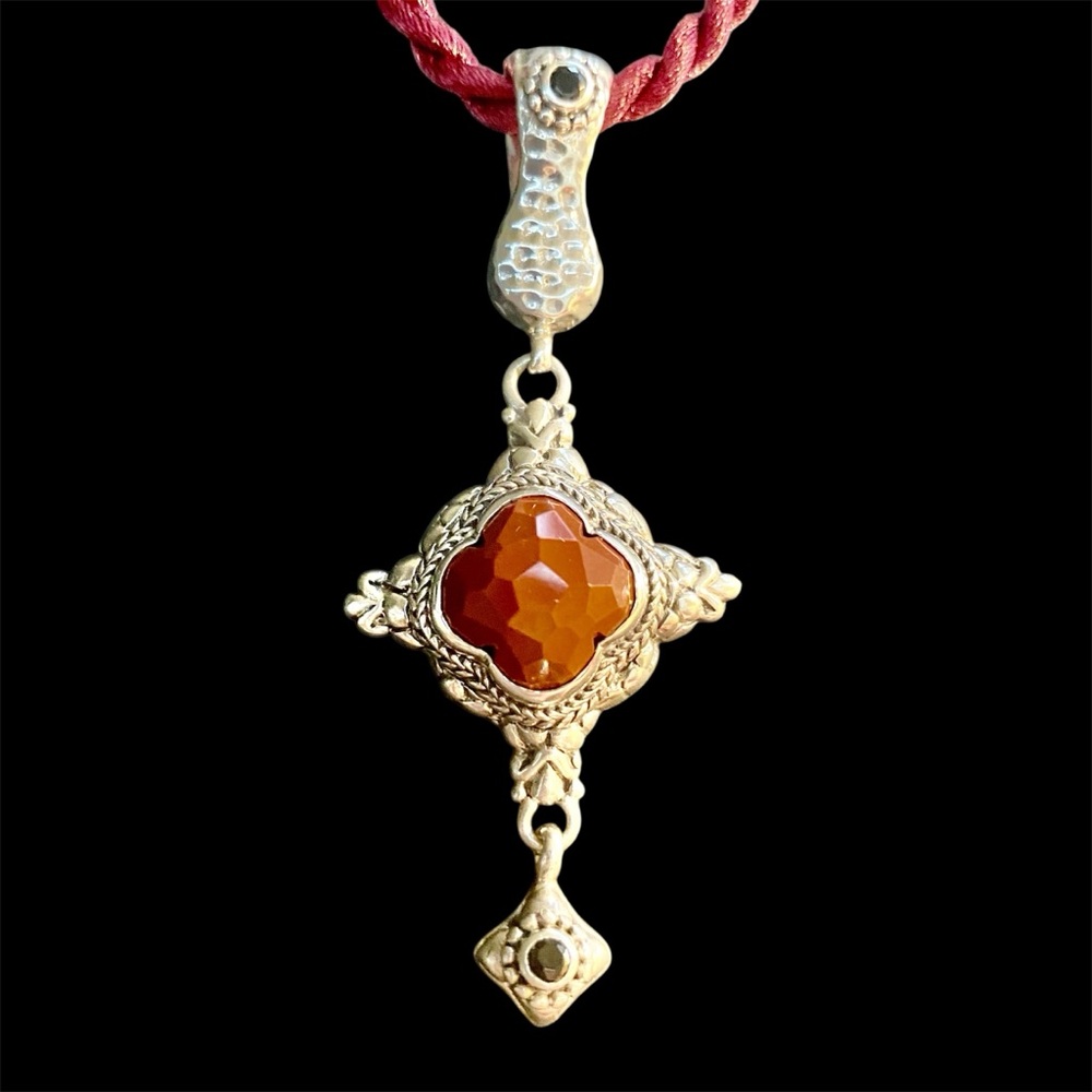 Sarda pendant with faceted carnelian stone in center and two small black stones